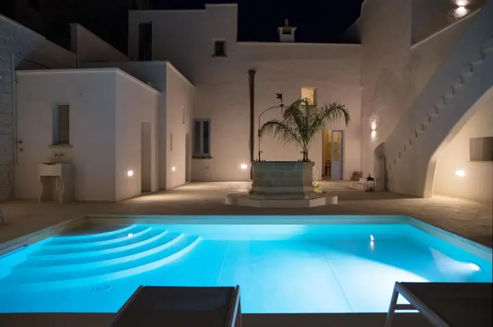 La piscina e l'antico pozzo nel cortile, di sera